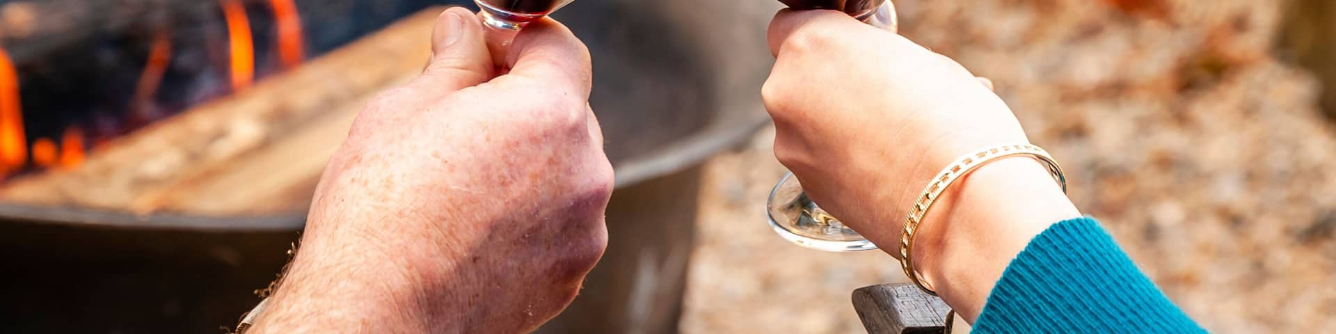 USA, Washington State, Woodinville. A man and a woman enjoy a glass of red wine in front of a campfire.