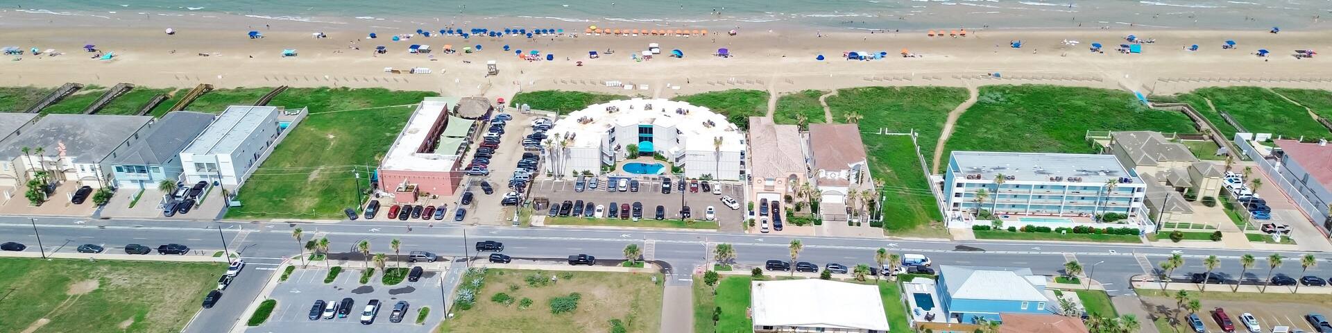 Panorama aerial view beach hotels, condos, vacation rental, resorts swimming pool along sandy shoreline, turquoise water in South Padre Island, tropical barrier island Texas Gulf Coast, travel