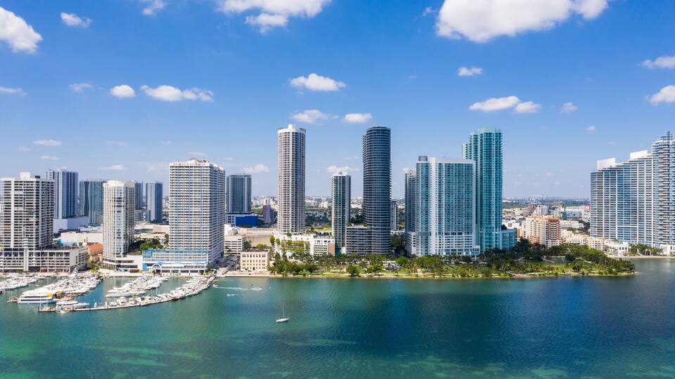 Horizonte urbano com arranha-céus modernos e uma marina com barcos.