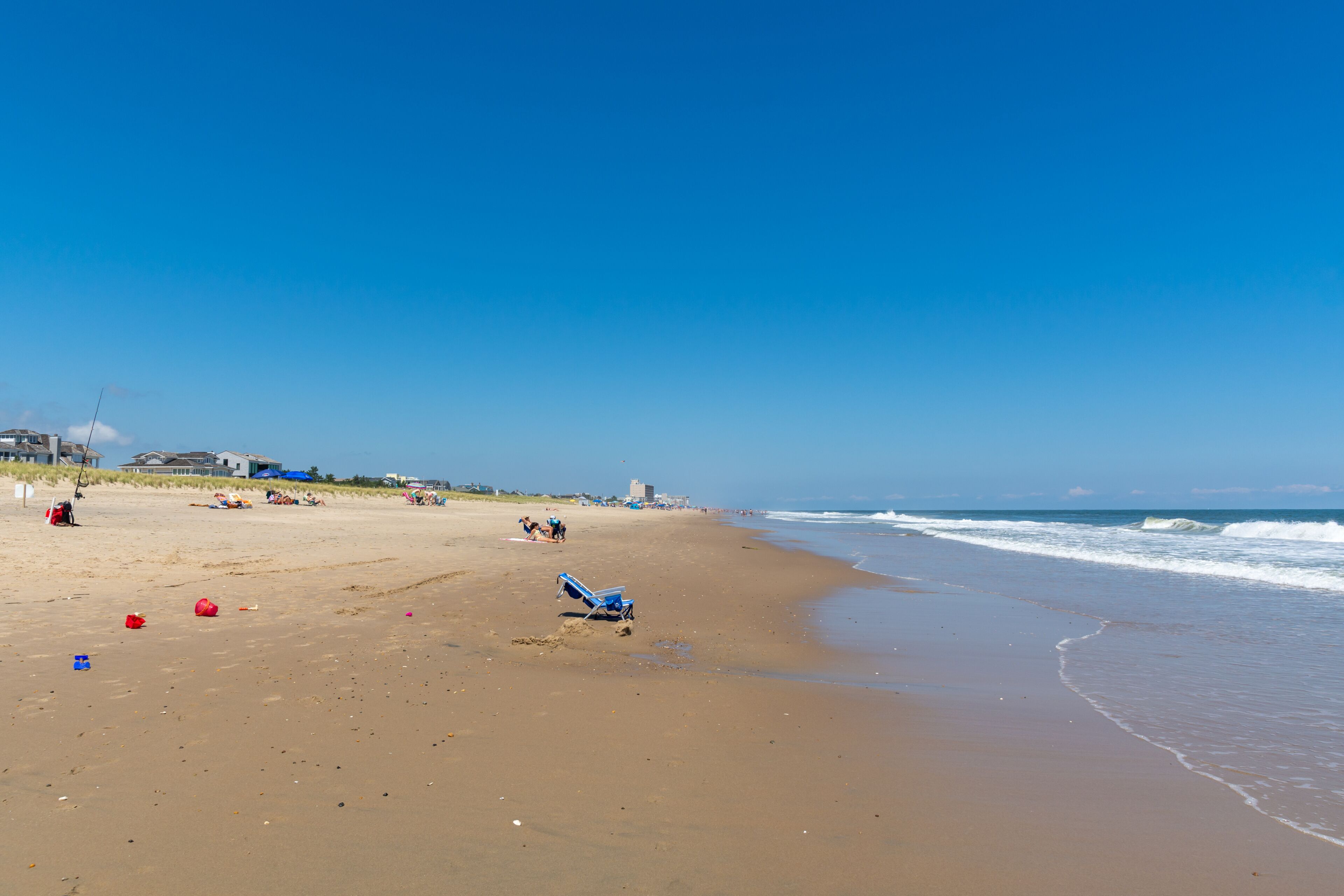 REHOBOTH, DELAWARE - USA - AUGUST 17, 2020: A relatively empty beach south of Rehoboth Beach on a sunny summer afternoon. Empty beach chair in foreground and town of Rehoboth in background.