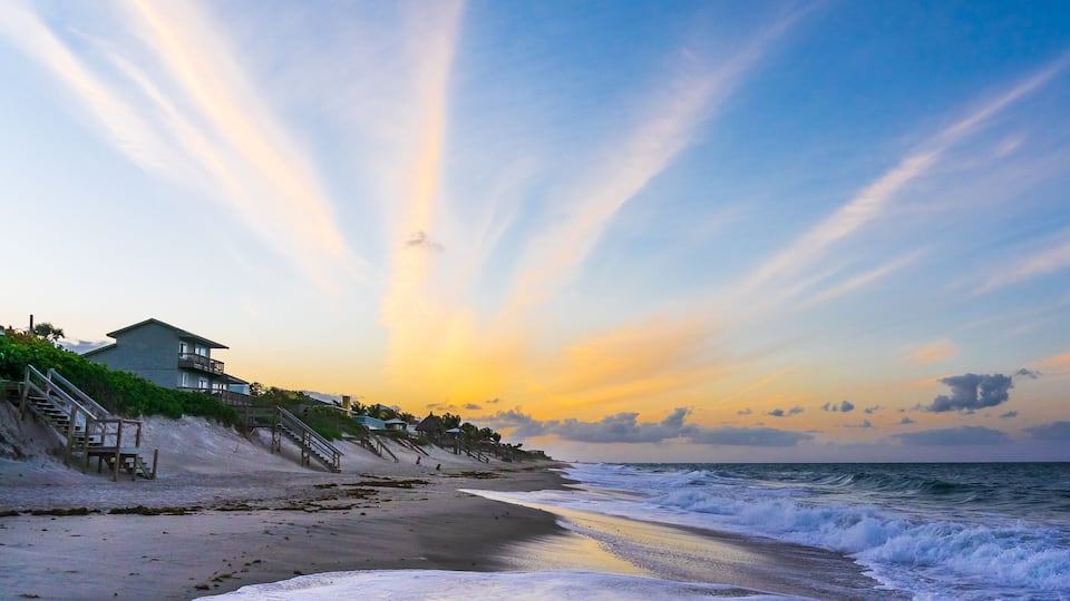 Orange clouds in the form of diverging rays at sunset on the ocean in Melbourne Beach, Florida