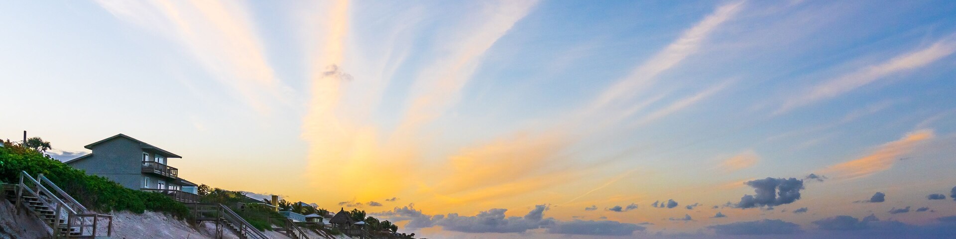 Orange clouds in the form of diverging rays at sunset on the ocean in Melbourne Beach, Florida