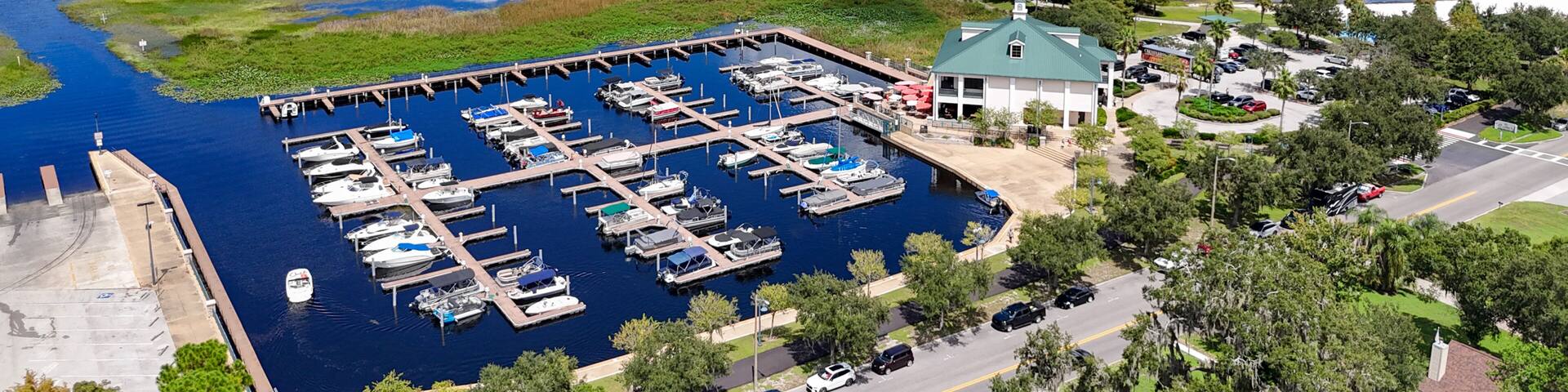 A marina with boats docked, a green-roofed building, and a road leading to it.