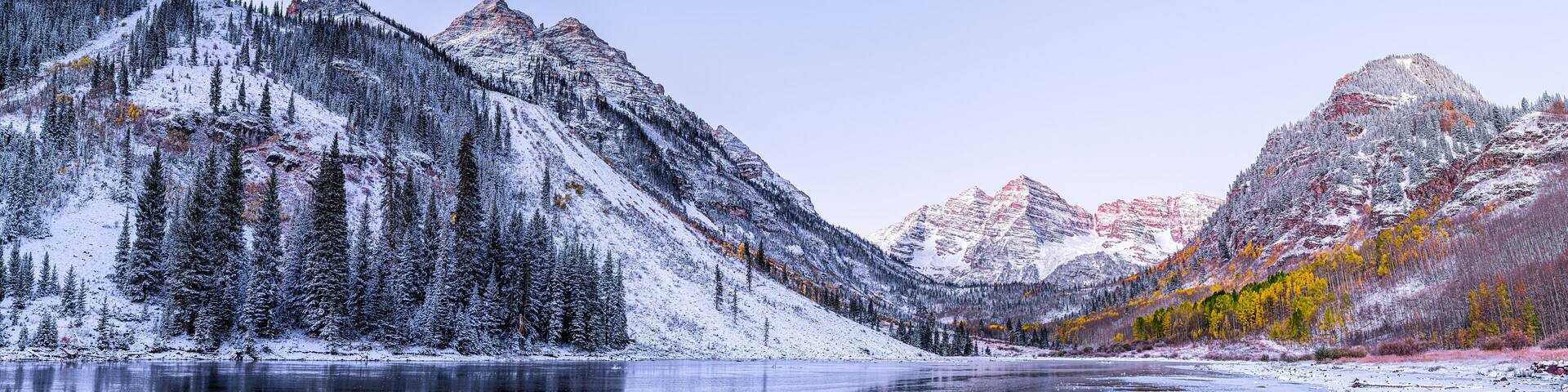 Maroon Bells morning sunrise panorama with sunlight on peak in Aspen, Colorado rocky mountain and autumn yellow foliage panoramic view winter snow