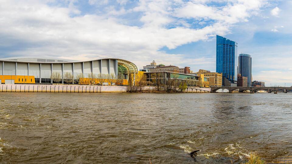 A river with a bridge, a modern building, and a historic building in the background.