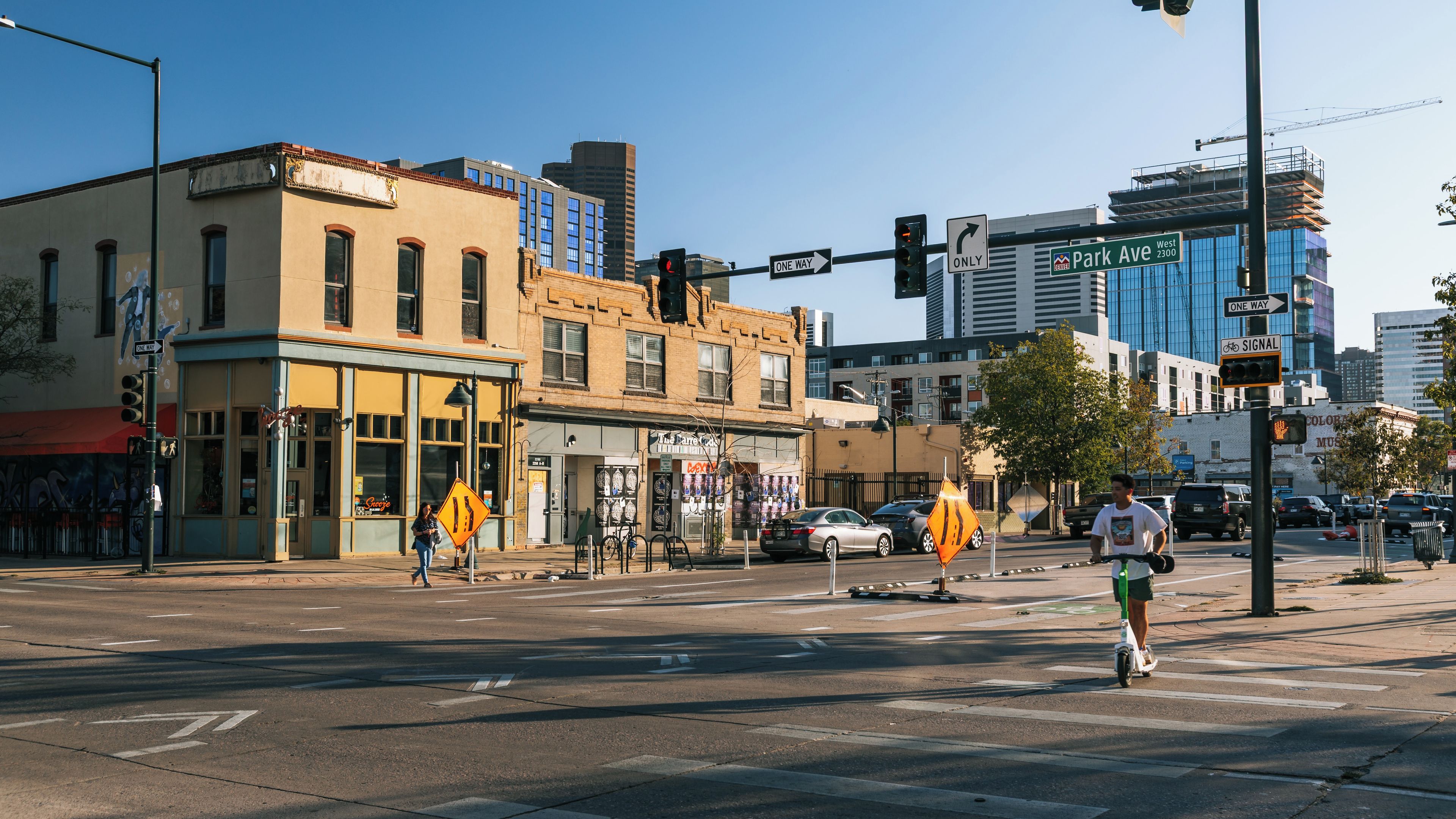Une intersection urbaine avec des feux de signalisation, un panneau indiquant une rue à sens unique et un cycliste qui traverse.