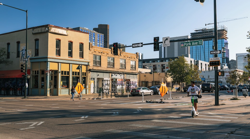 Une intersection urbaine avec des feux de signalisation, un panneau indiquant une rue à sens unique et un cycliste qui traverse.