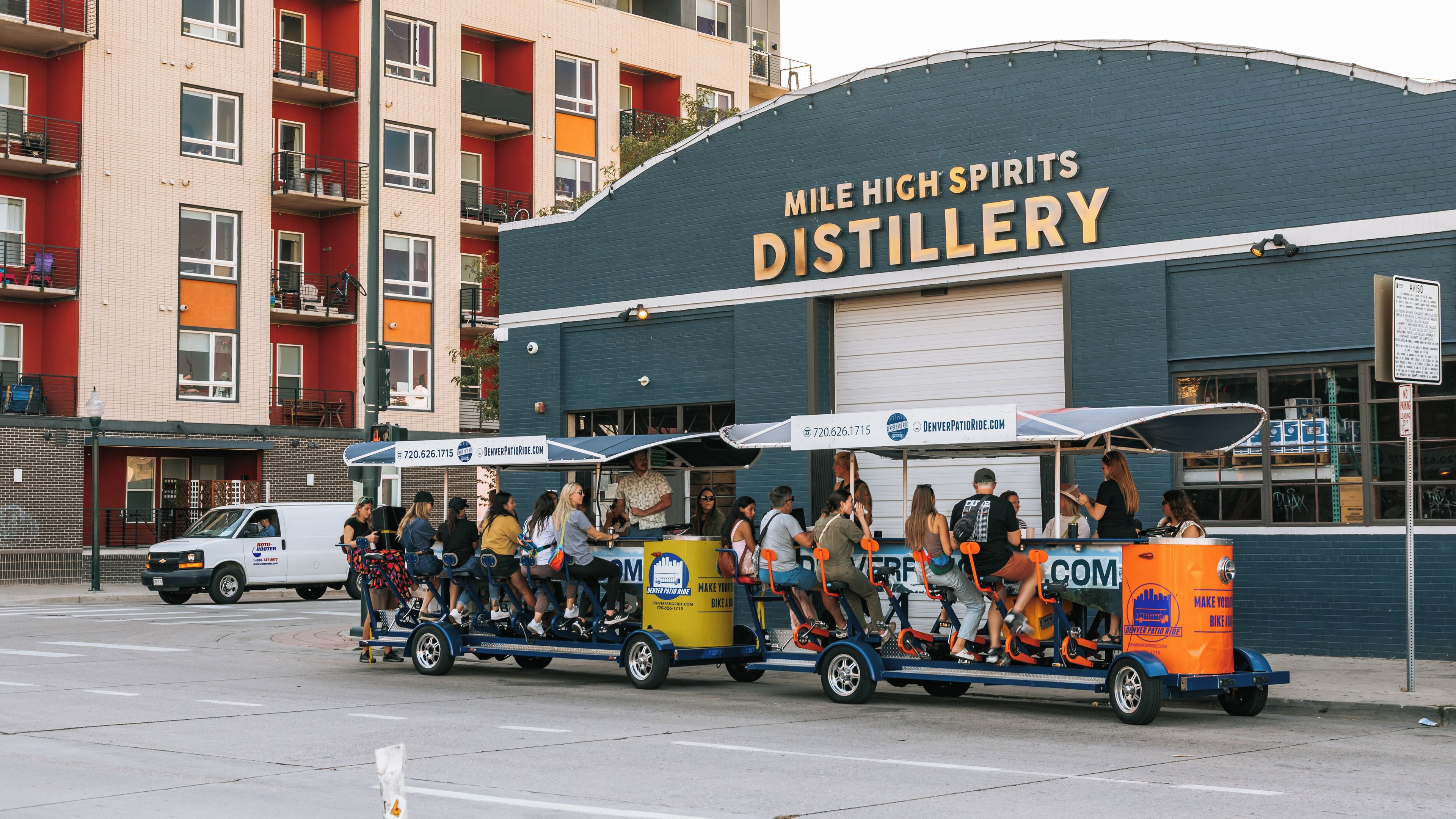 Un groupe de personnes participant à une randonnée à vélo fait la queue devant la distillerie Mile High Spirits.