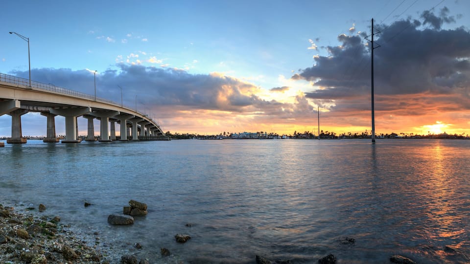 A bridge over a body of water with a sunset in the background.