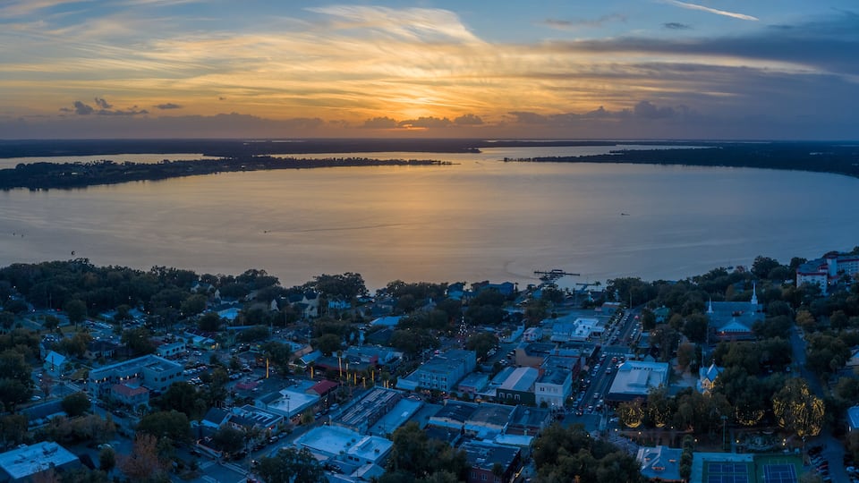 A coastal town at sunset with a large body of water, buildings, and a church.