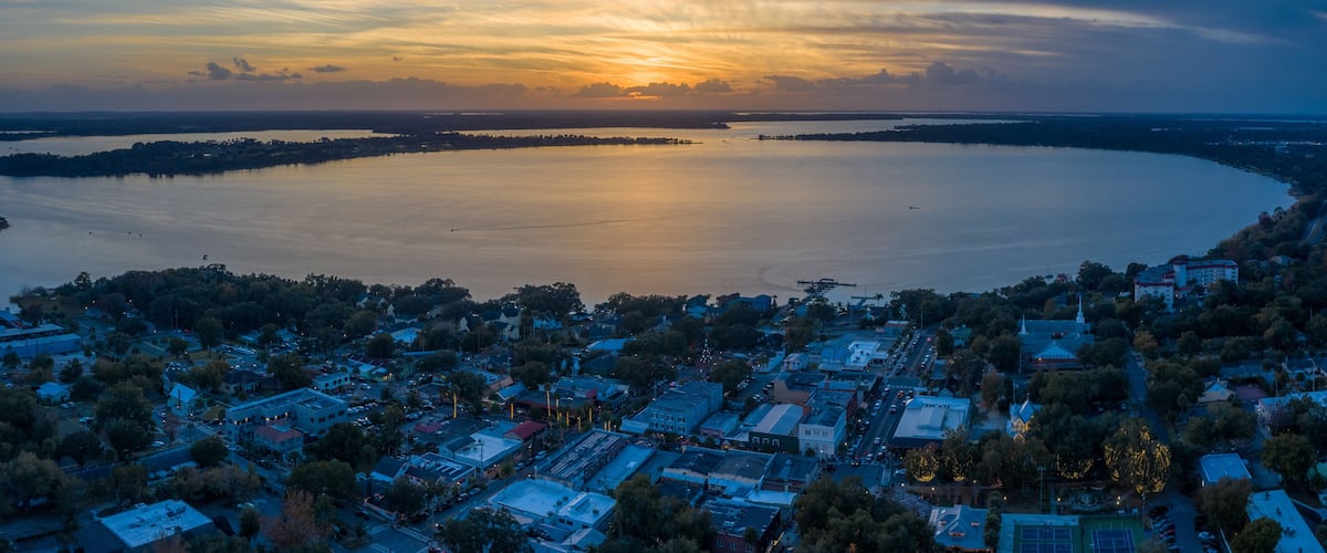 A coastal town at sunset with a large body of water, buildings, and a church.