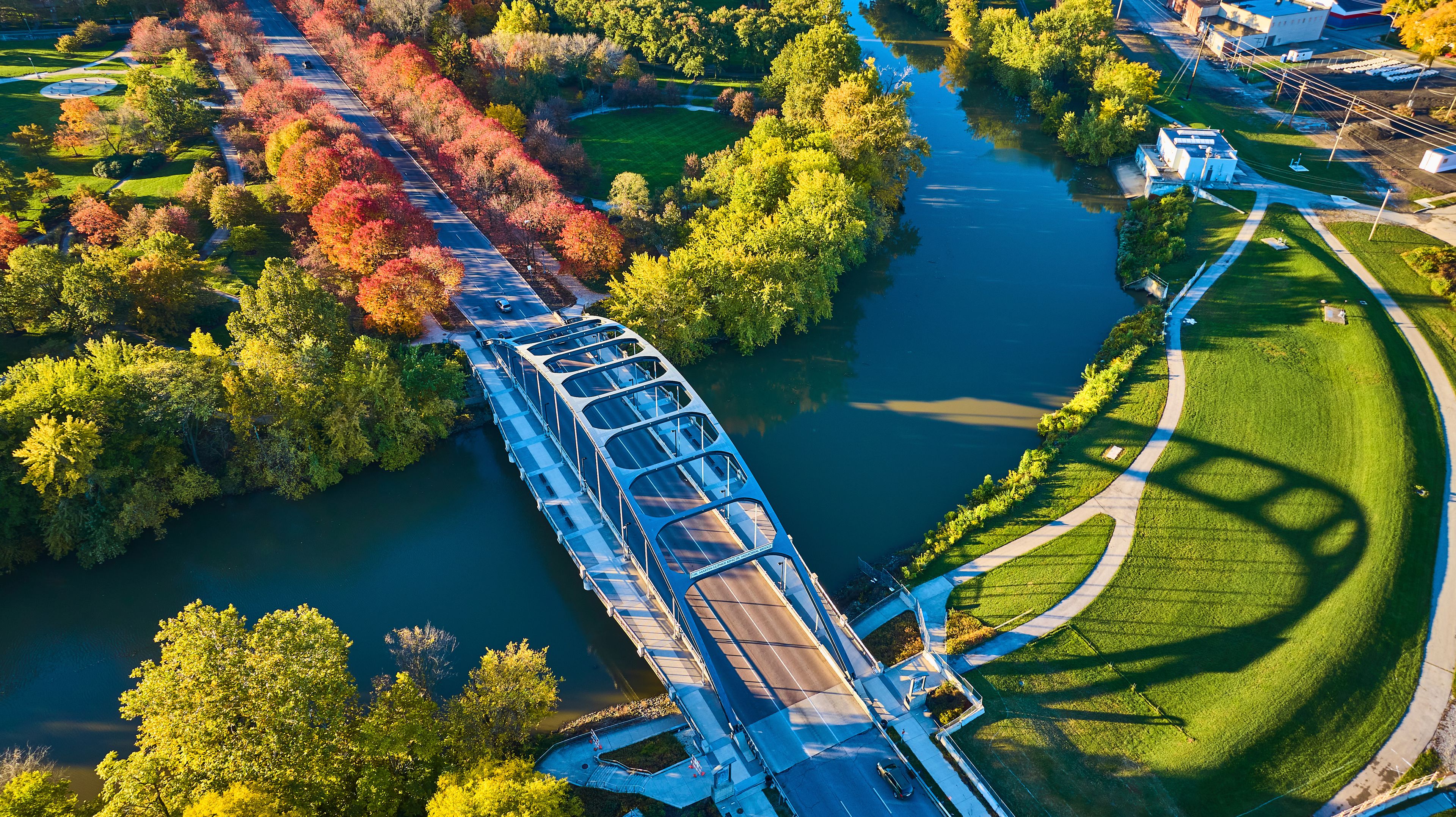 Eine Brücke über einem Fluss, umgeben von Bäumen und einem Park.