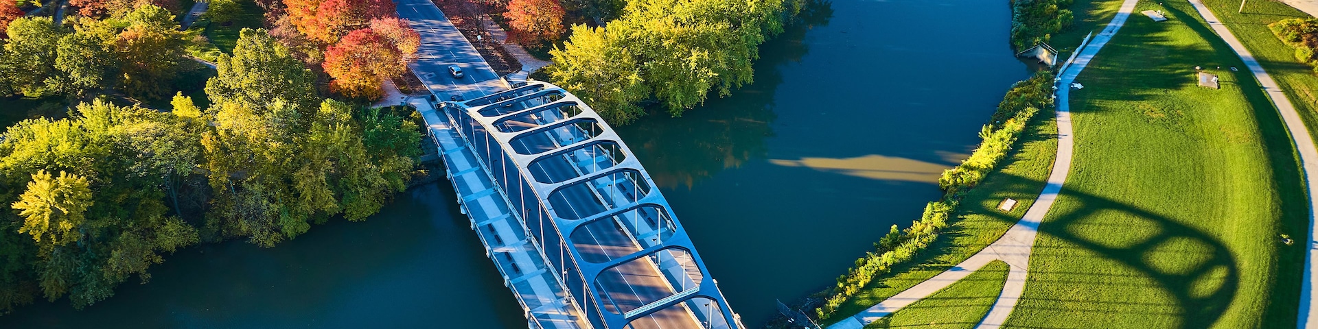 Un puente sobre un río, con árboles y un parque en los alrededores.