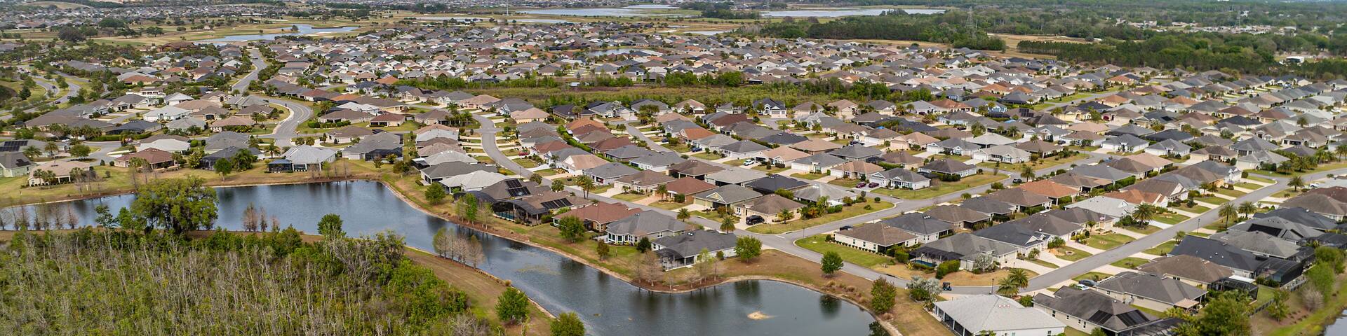 A residential area with houses, a lake, and surrounding greenery.