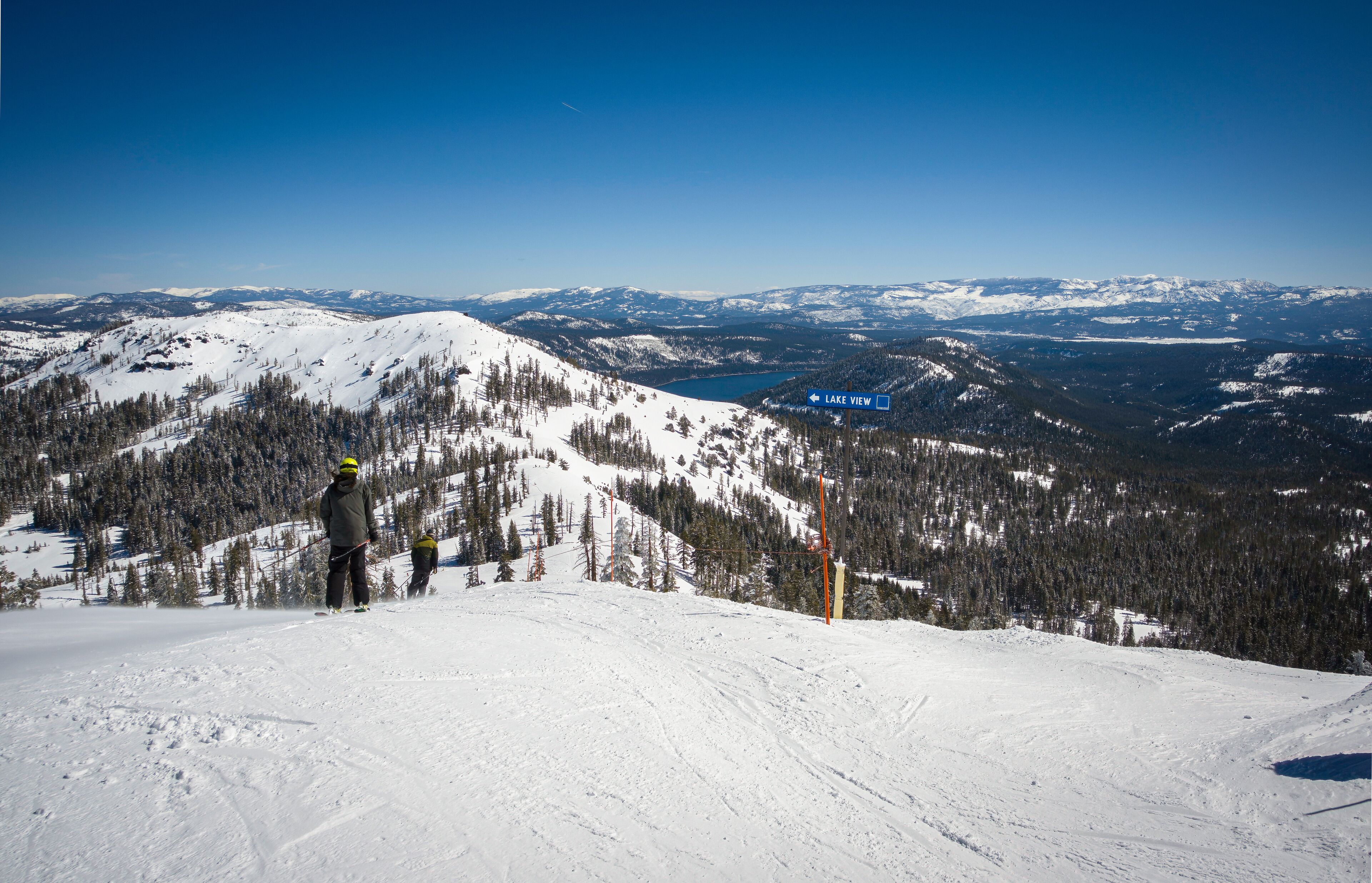 Unidentifiable skiiers head down Mt. Lincoln to the Lake View intermediate run at Sugar Bowl Ski Resort. Donner Lake is in the background.