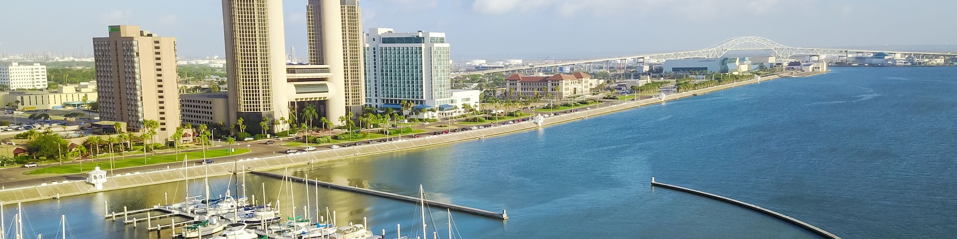 Panorama aerial view Bayfront area of Corpus Christi with skylines and marina piers row of boat, sailboat and yacht at sunrise. City harbor bridge far right in distance. A Texas city on Gulf of Mexico