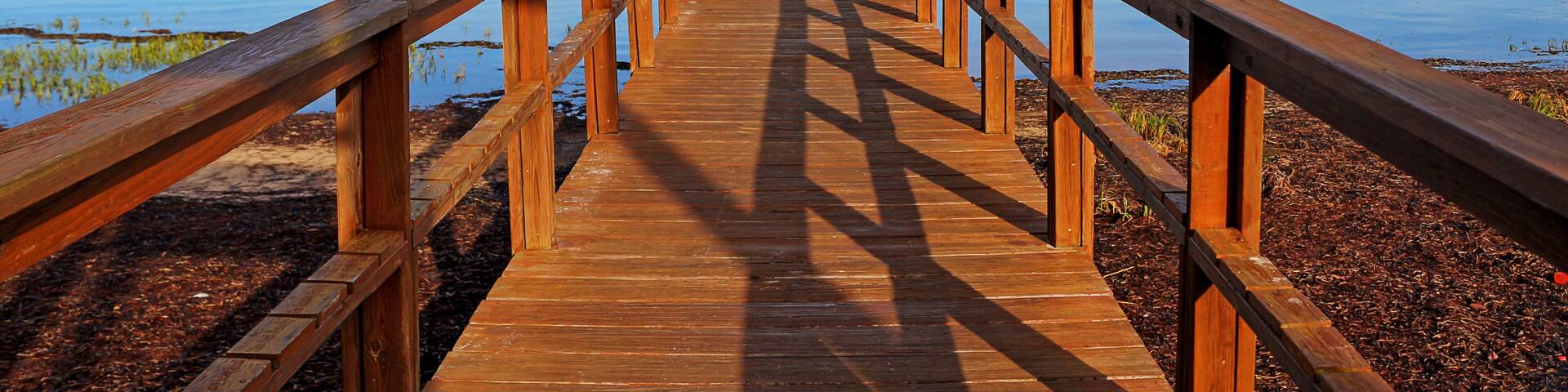 A wooden pier extending into calm water with a clear sky above.