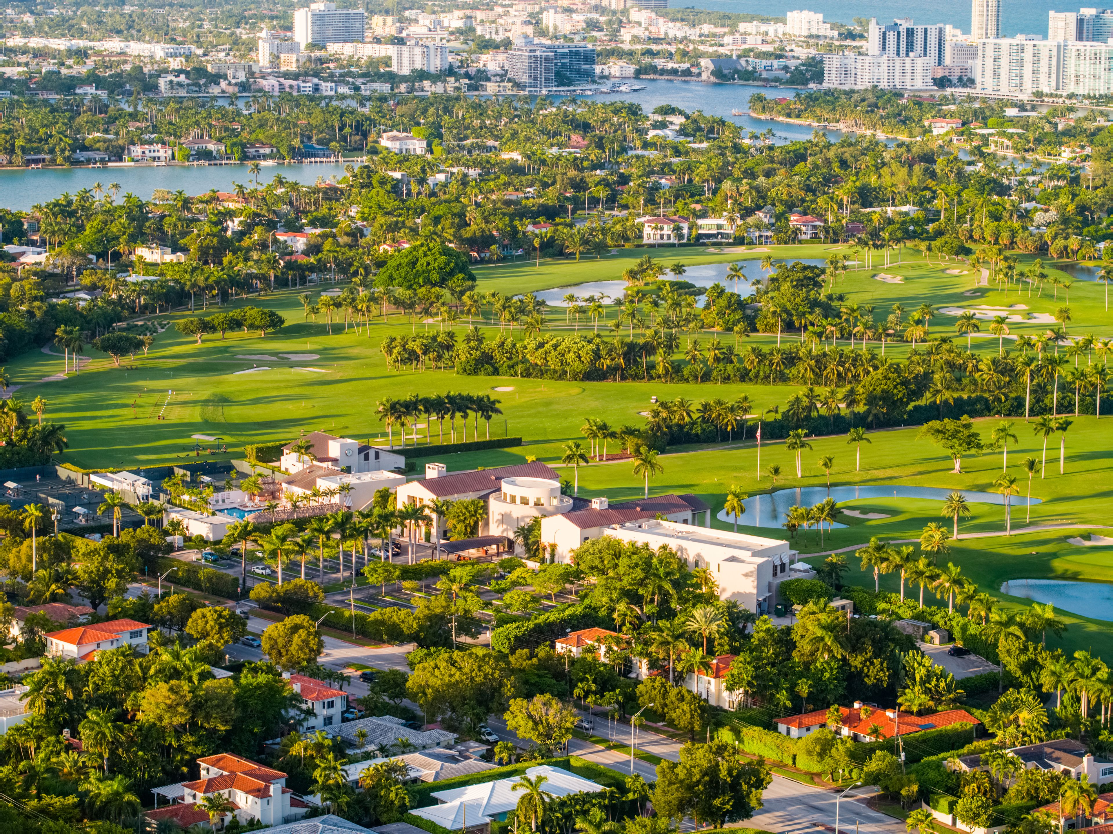 A coastal cityscape with a golf course, residential areas, and a marina.