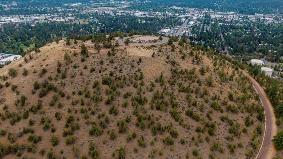High-angle view of Pilot Butte Neighbourhood Park from a hilltop. City sprawls below, with mountains in the distance. ,Bend, Oregon, USA