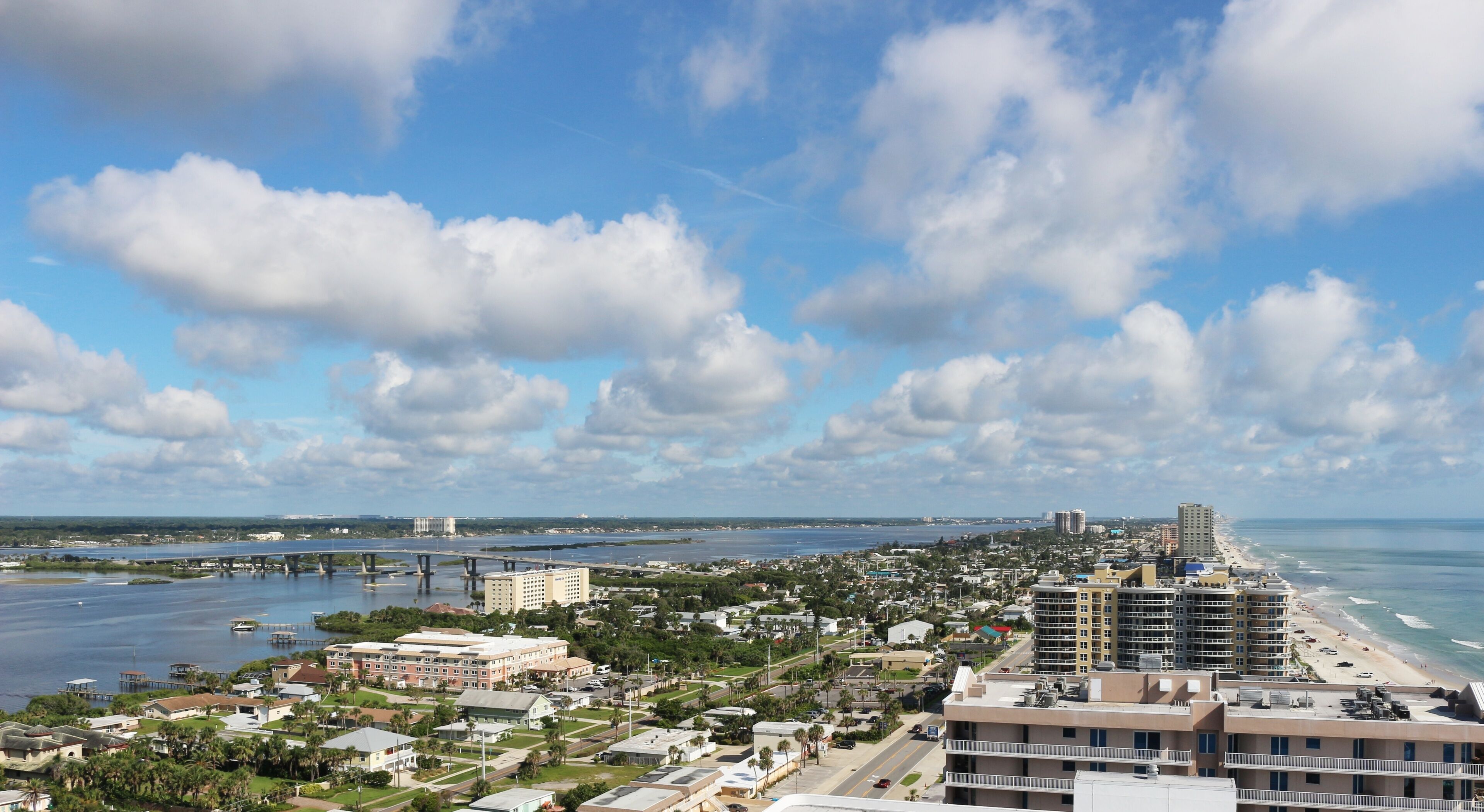 Panoramic aerial view of the Halifax river to the Atlantic ocean beach with the Port Orange Bridge and the Daytona Beach Speedway grandstands in the distance 