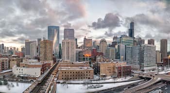 A cityscape with tall buildings, a train track, and a snowy landscape.