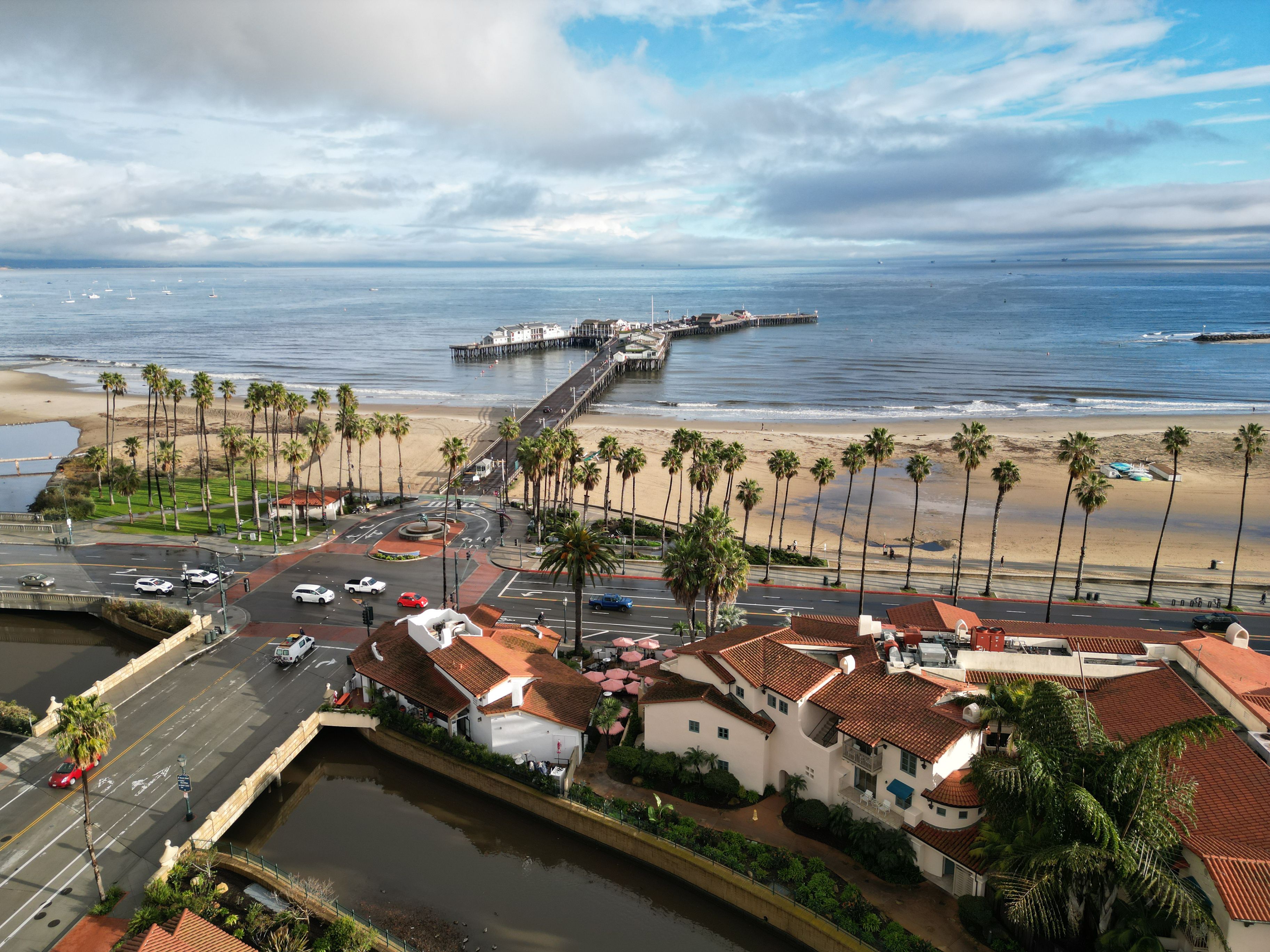 Aerial drone shot overlooking Santa Barbara, California on a sunny afternoon. Visible landmarks include Stearns Wharf, Mission Creek, Cabrillo Blvd., State Street as well as Pacific coast beaches.