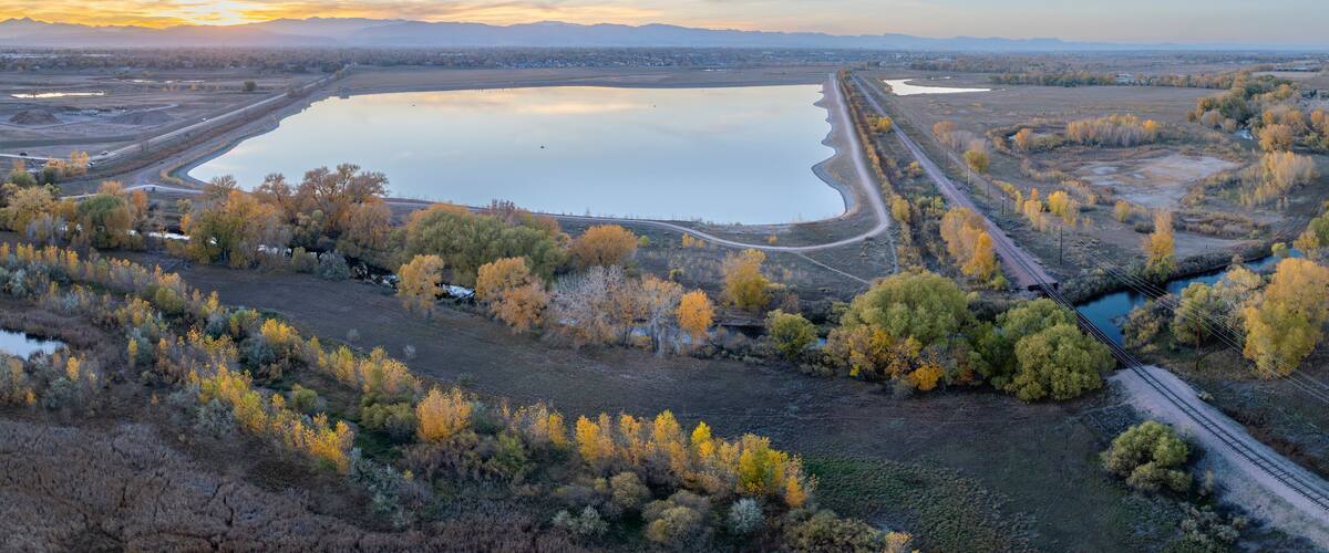 aerial panorama of Colorado landscape near Fort Collins with Poudre River, Rigden Reservoir and sunset over Rocky Mountains