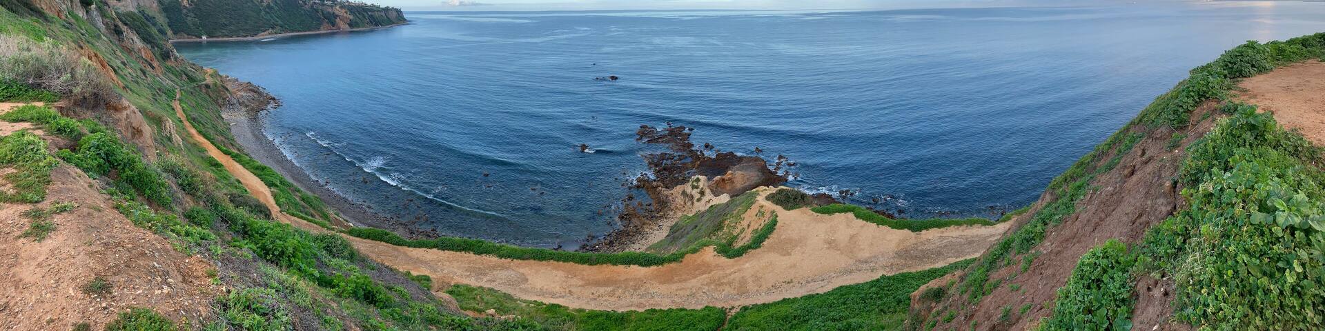 A coastal landscape with cliffs, a beach, and a clear sky.