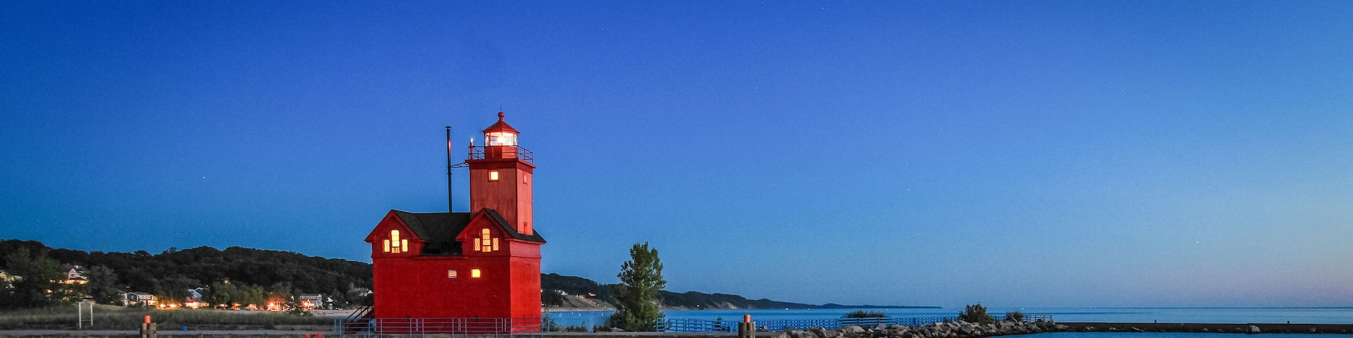 Holland Michigan Lighthouse At Night. The beautiful big red lighthouse at Holland State Park at night with illuminated beacon.