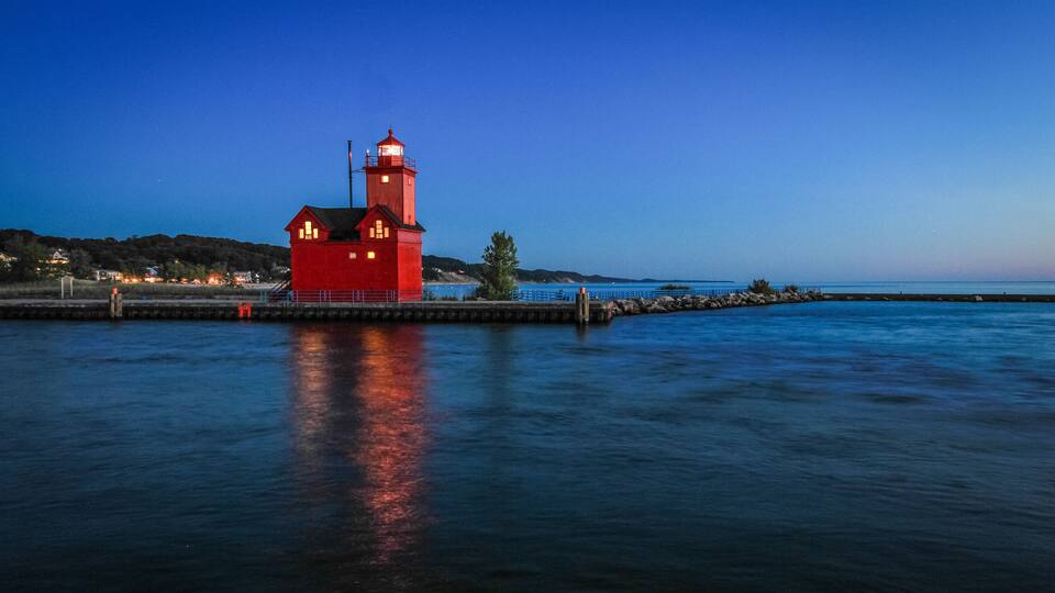Holland Michigan Lighthouse At Night. The beautiful big red lighthouse at Holland State Park at night with illuminated beacon.