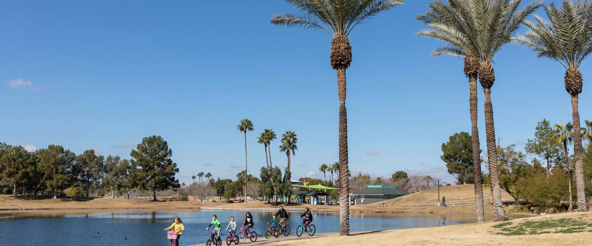 A family rides bikes next to lake in desert park