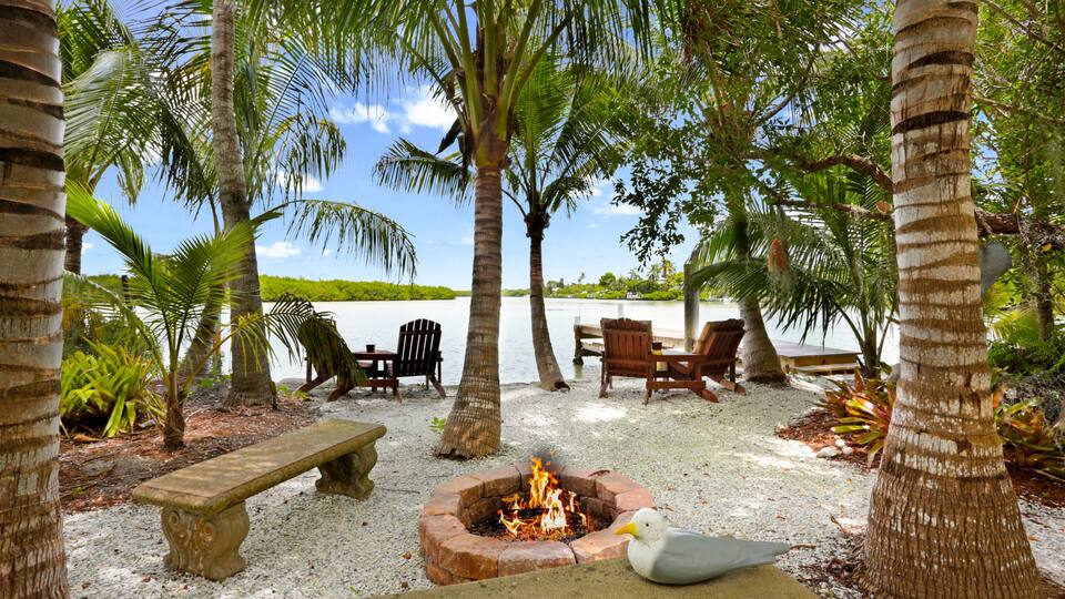 Fire Pit with Benches Palm Trees and Chairs on the Shore of Blue Bay Waters in Sanibel Island, Florida