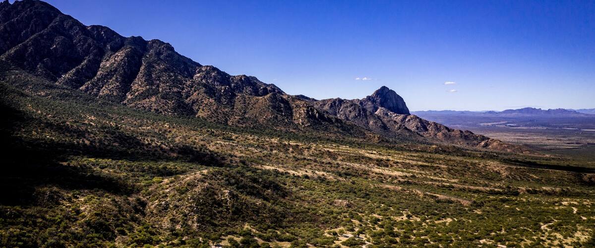 Aerial panorama of Madera Canyon in the Santa Rita Mountains, Arizona in the Fall with purple mountains, green, yellow, orange trees and bushes, blue sky