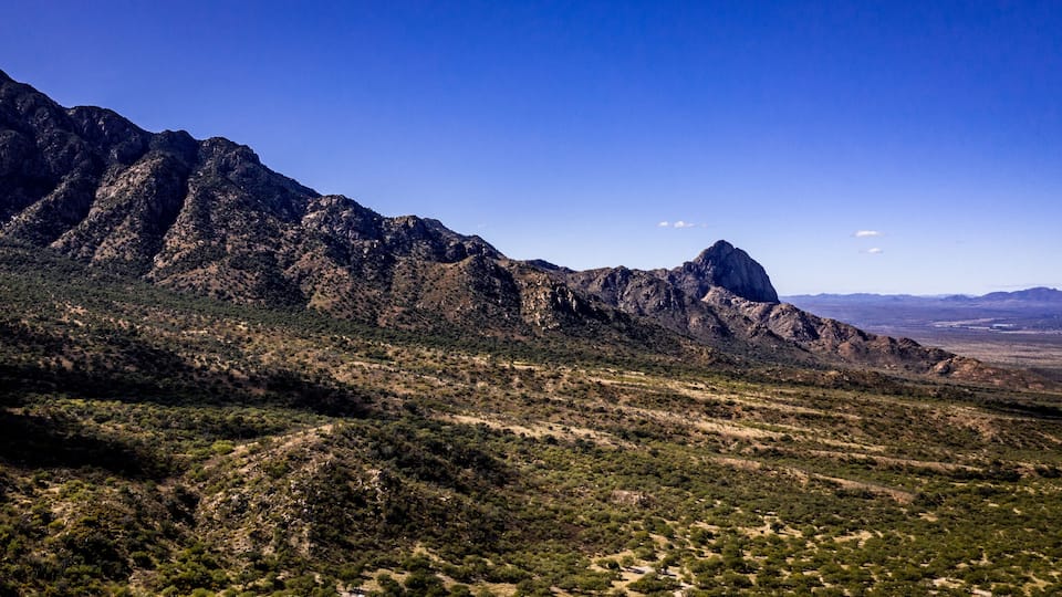 Aerial panorama of Madera Canyon in the Santa Rita Mountains, Arizona in the Fall with purple mountains, green, yellow, orange trees and bushes, blue sky