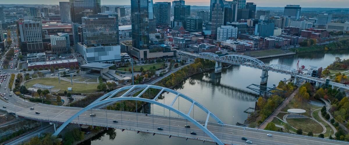 A cityscape with modern skyscrapers, a river, and a distinctive bridge.