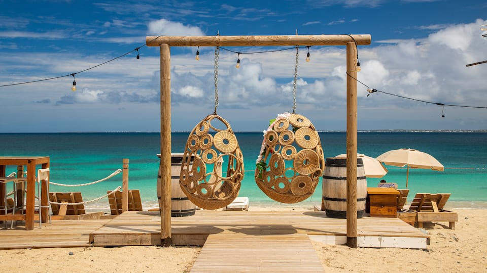A wooden deck with hanging wicker chairs and a wooden swing set overlooking turquoise waters.