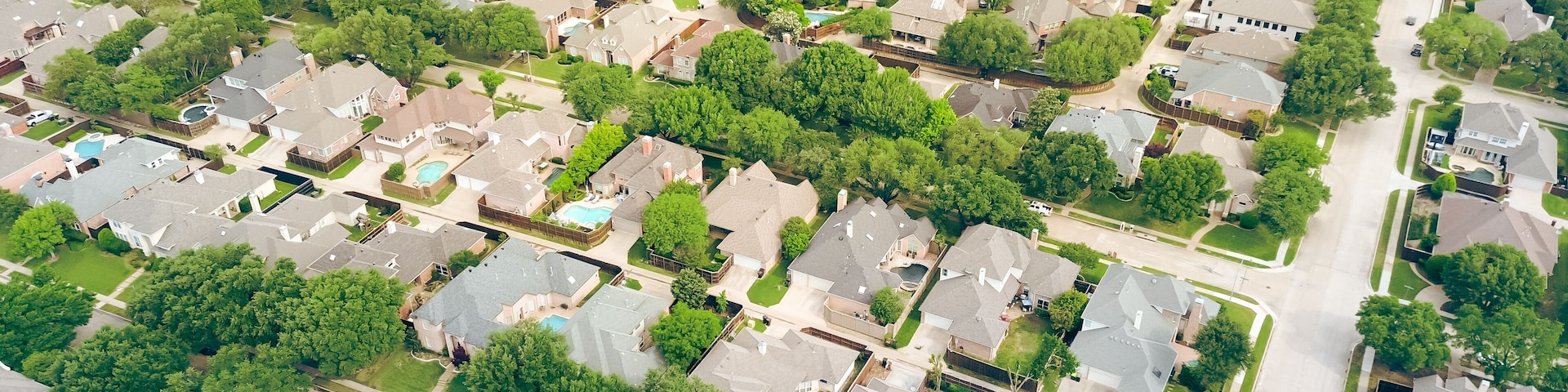 Vista aérea de un barrio residencial con casas, árboles y un lago.
