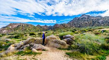 Senior woman hiker enjoying the view of the Valley of the Sun and the McDowell Mountain Range around Phoenix, Arizona viewed from the Tom's Thumb Trail