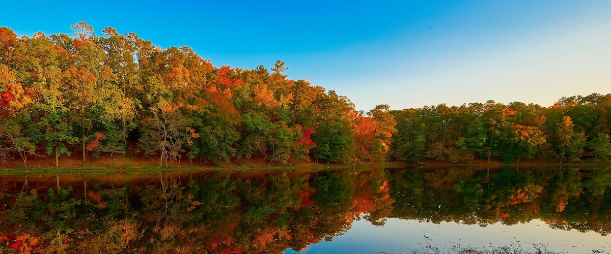 A calm lake surrounded by autumn-colored trees reflecting in the water.
