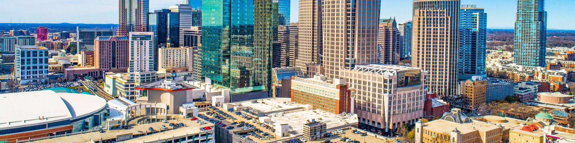 A cityscape with modern skyscrapers, a large stadium, and a parking lot.