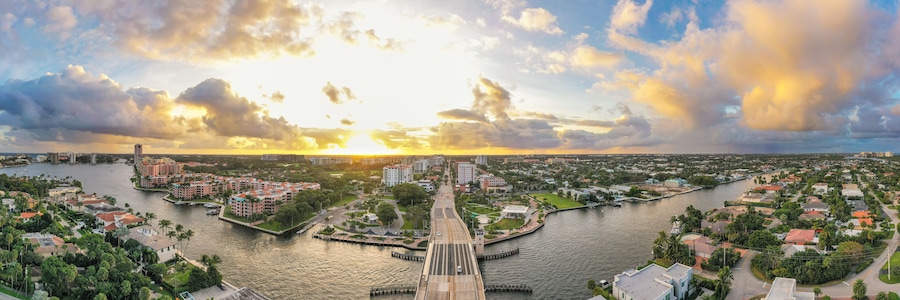Un río con un puente, edificios y un atardecer.