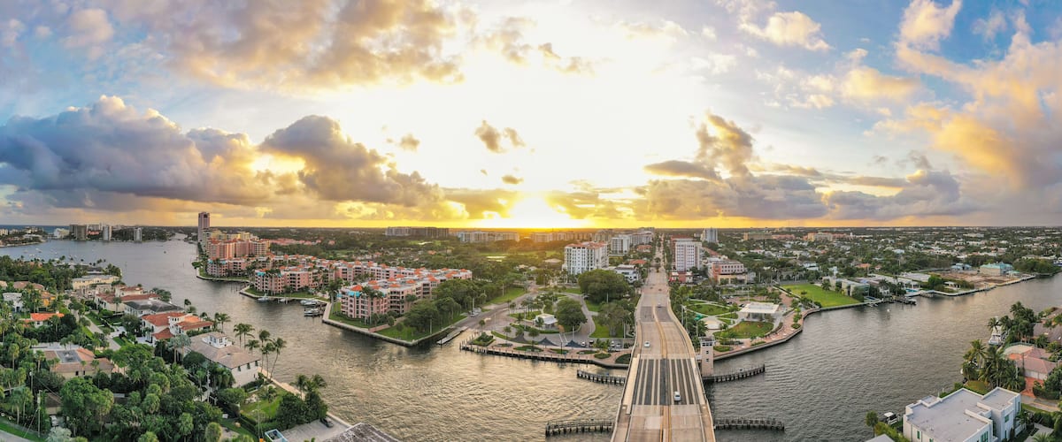 A river with a bridge, buildings, and a sunset.