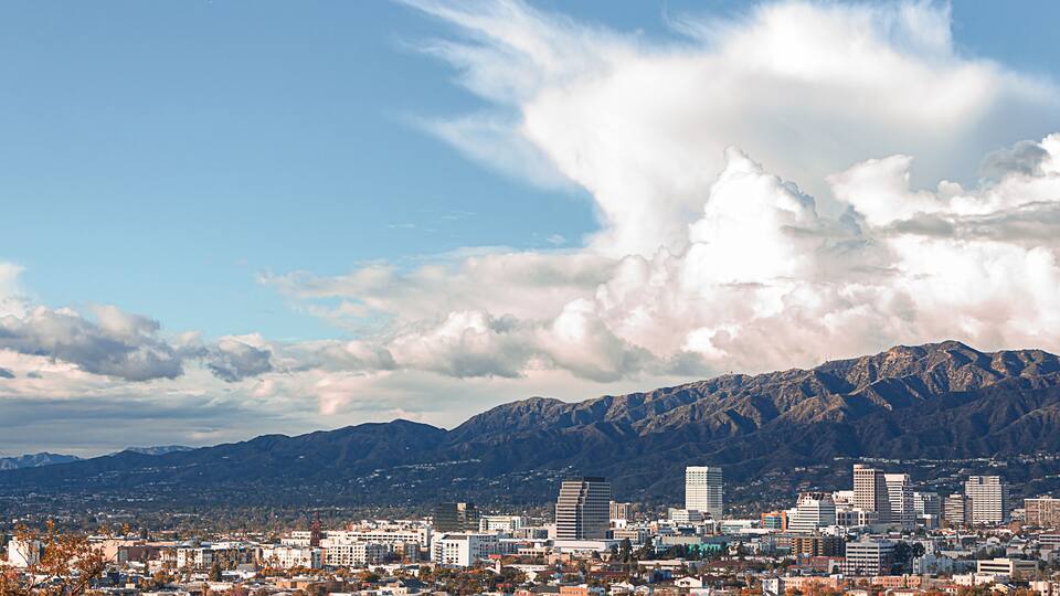 panaramic view of city businesses and homes with hillside homes and mountains