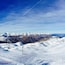 Un paysage de montagne enneigé, avec des remontées mécaniques et un ciel bleu dégagé.