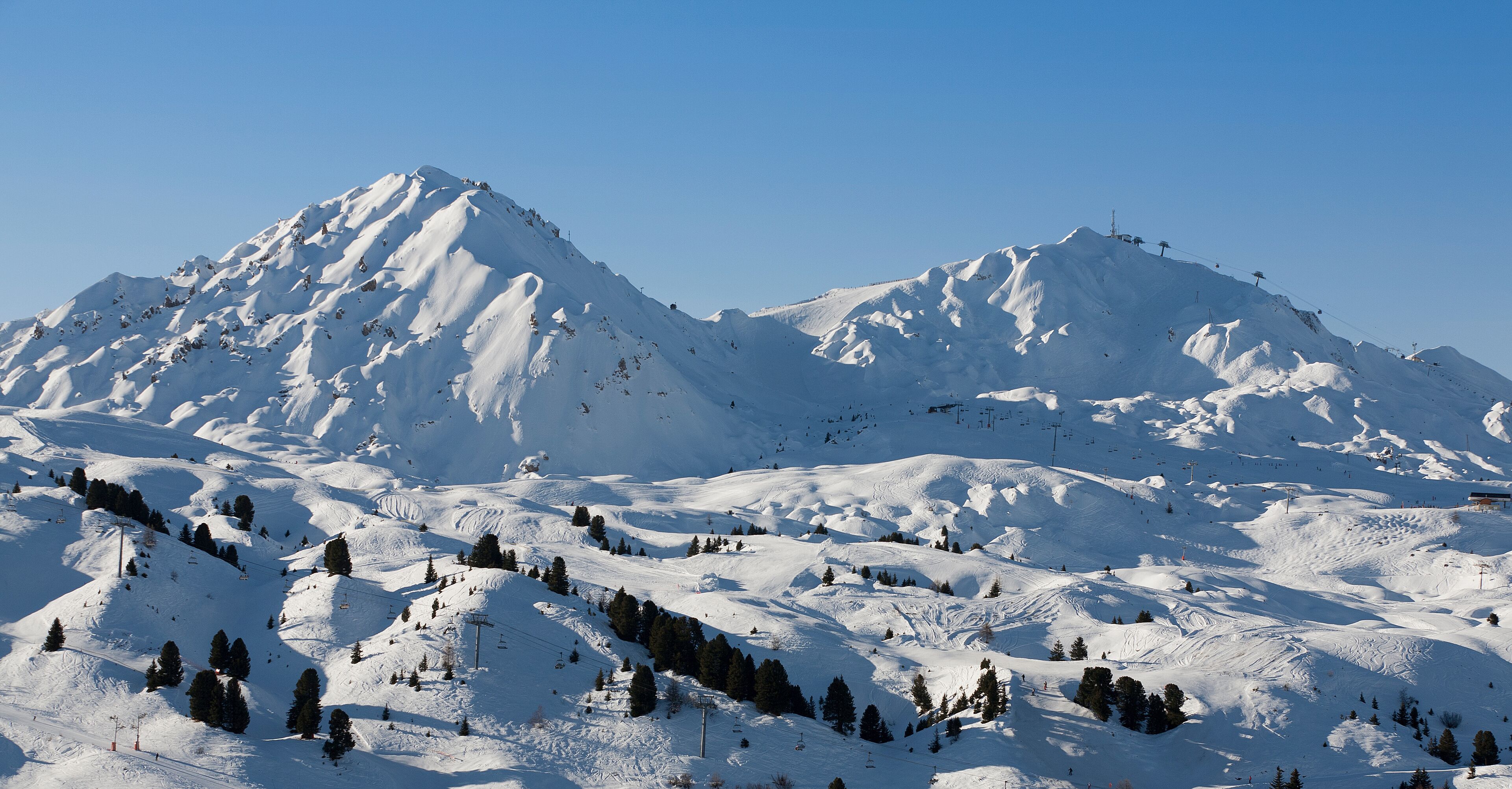A snow-covered mountain range with ski slopes and ski lifts.