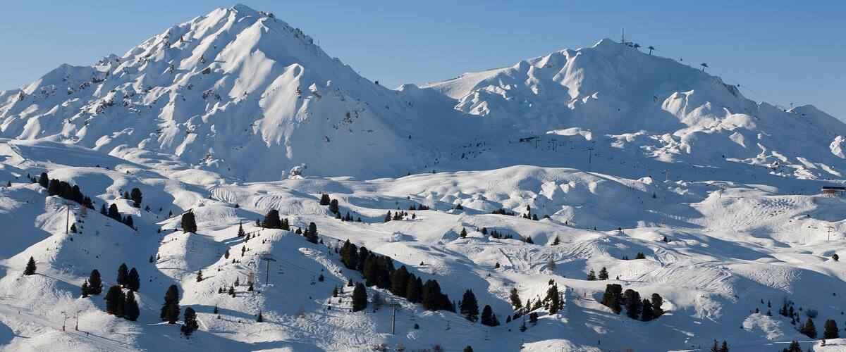 A snow-covered mountain range with ski slopes and ski lifts.