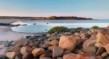 A rocky beach with large boulders and a calm sea.