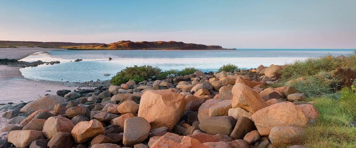 A rocky beach with large boulders and a calm sea.
