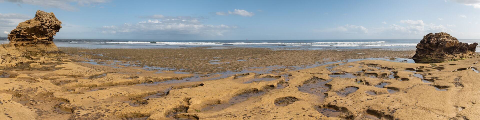 Panorama Rocky beach with rock formations and tidal pools blue sky