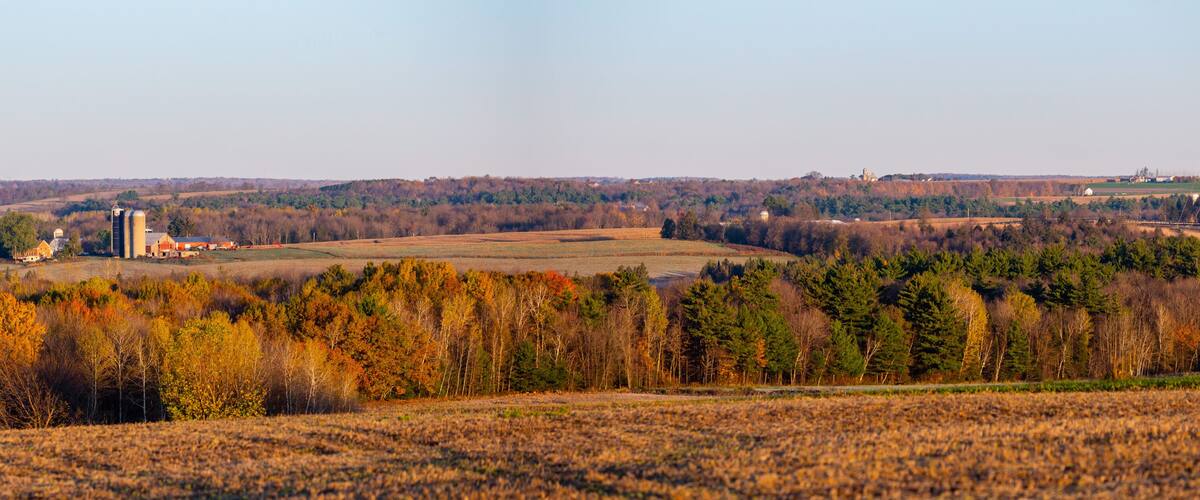 A rural landscape with fields, trees, and farm buildings.